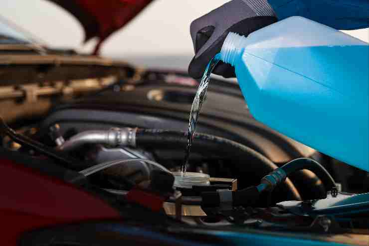 Uomo che riempie il liquido antigelo nella sua auto